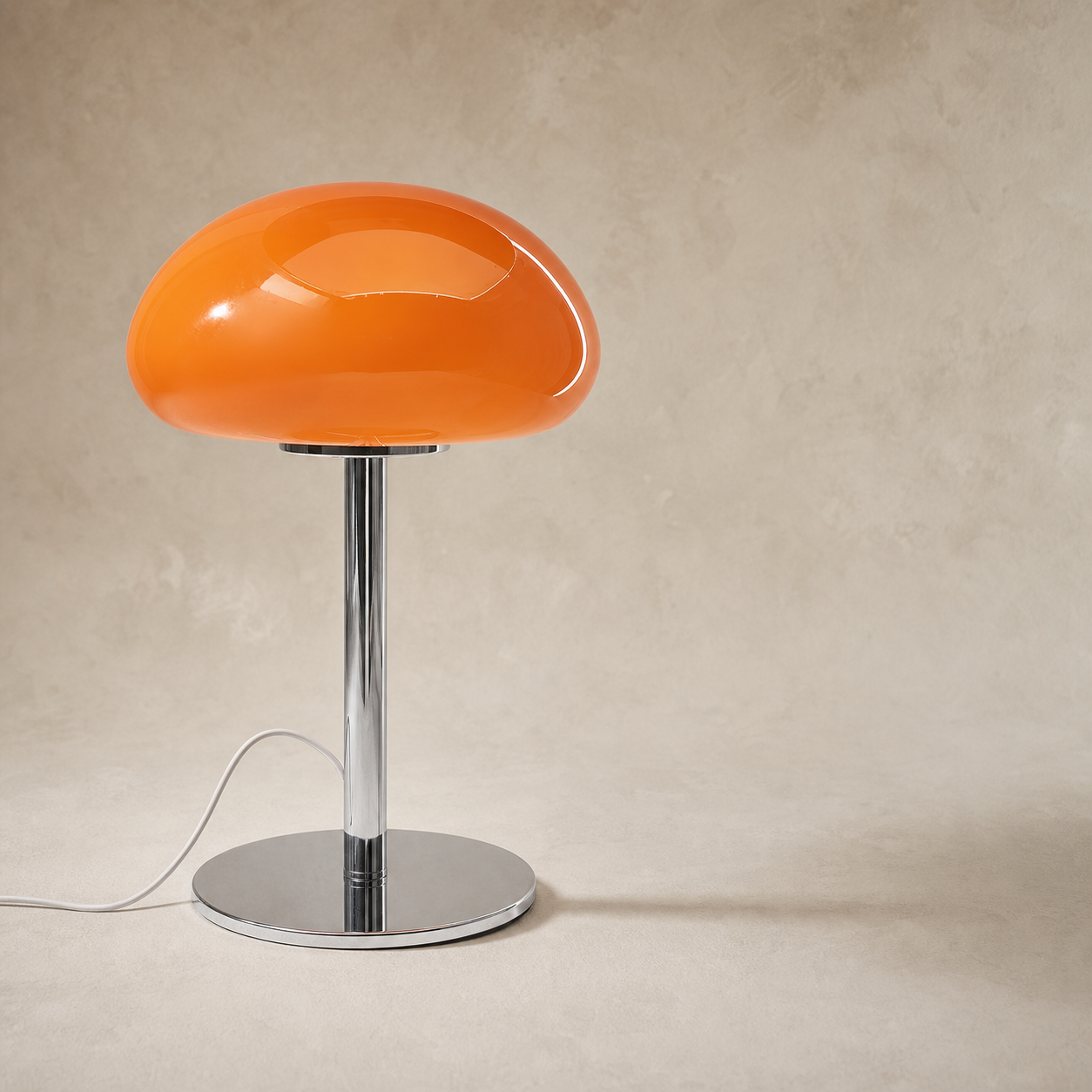 A mushroom-shaped table lamp with a glossy orange glass cap and a polished chrome stem and base, set against a textured beige background.
