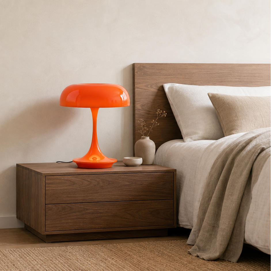Fungo mushroom lamp glowing warm orange on a dark wood nightstand beside a bed with beige linens