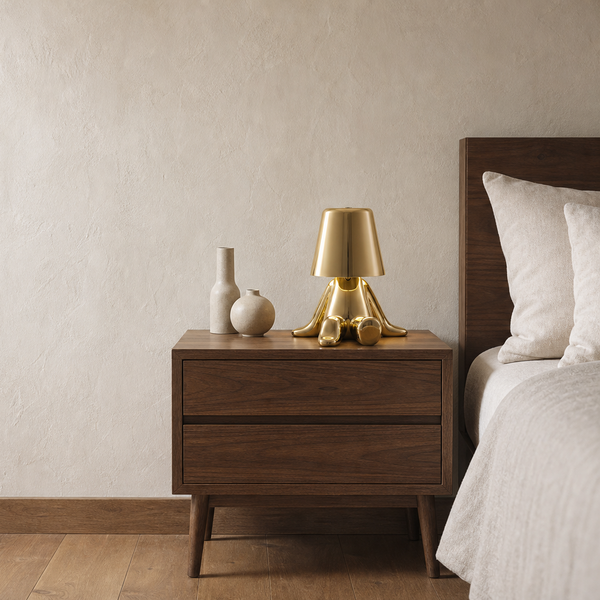 The Perch cordless lamp glowing on a wooden nightstand beside a bed with white linens