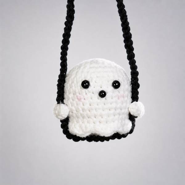 Crochet ghost charm sitting in a braided black cord swing