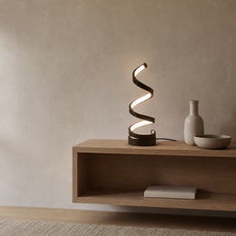 A modern spiral-shaped table lamp with a black base and glowing white light, styled on a floating wooden shelf next to a ceramic vase and bowl against a textured beige wall.