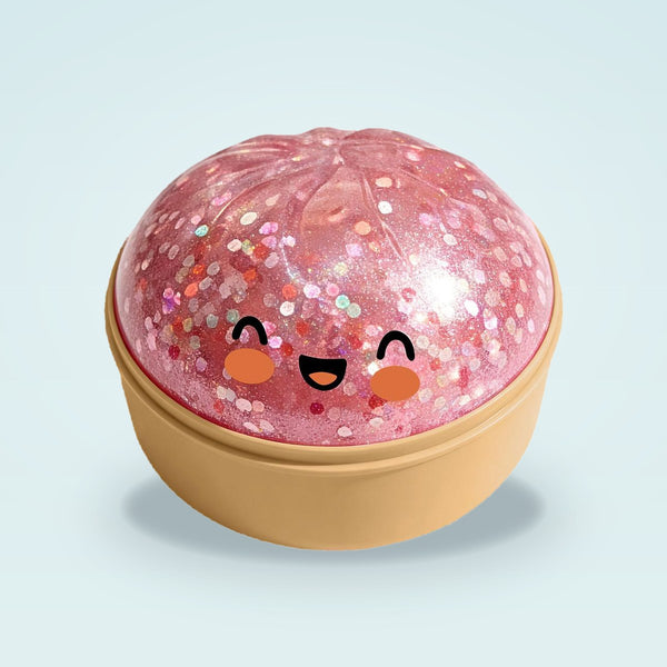 Pink glitter squishy bun with a smiling face in a tan steamer basket