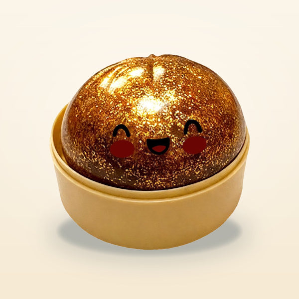 Copper glitter squishy bun with a smiling face in a tan steamer basket