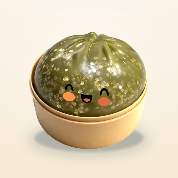 Olive green squishy bun with gold flecks and a smiling face in a tan steamer basket