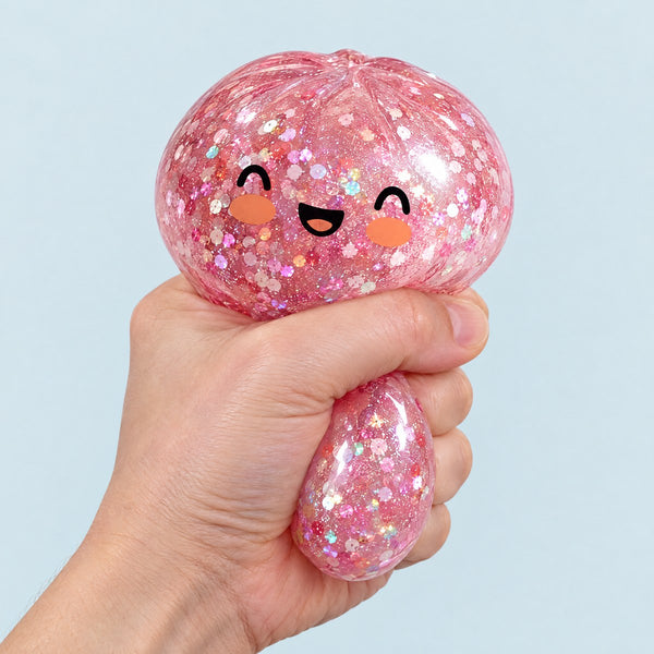 A hand squeezing a pink glitter squishy bun so it bulges (styled illustration)