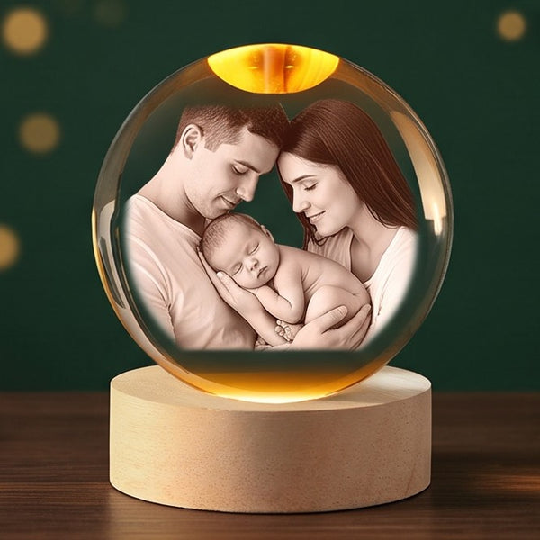 Example engraving: new parents holding their sleeping baby inside a glowing crystal ball on its wooden base.