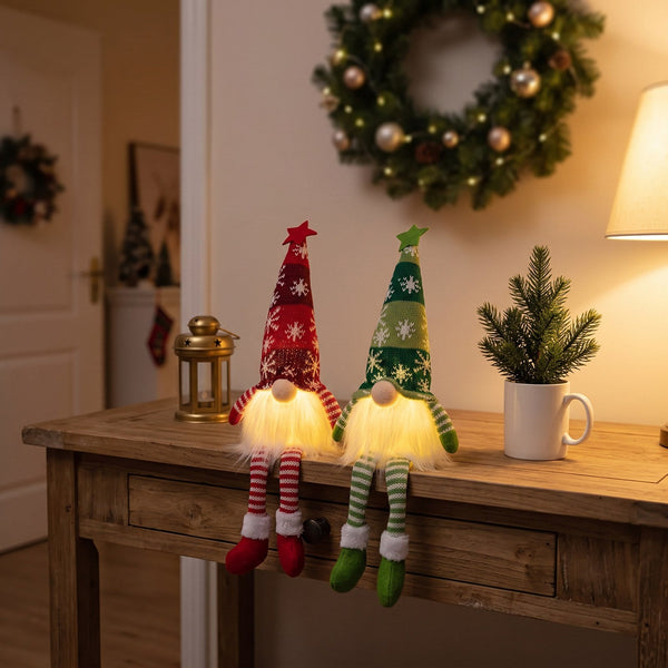 Red and green Long Legs gnomes glowing on an entryway console table next to a mini pine and a brass lantern
