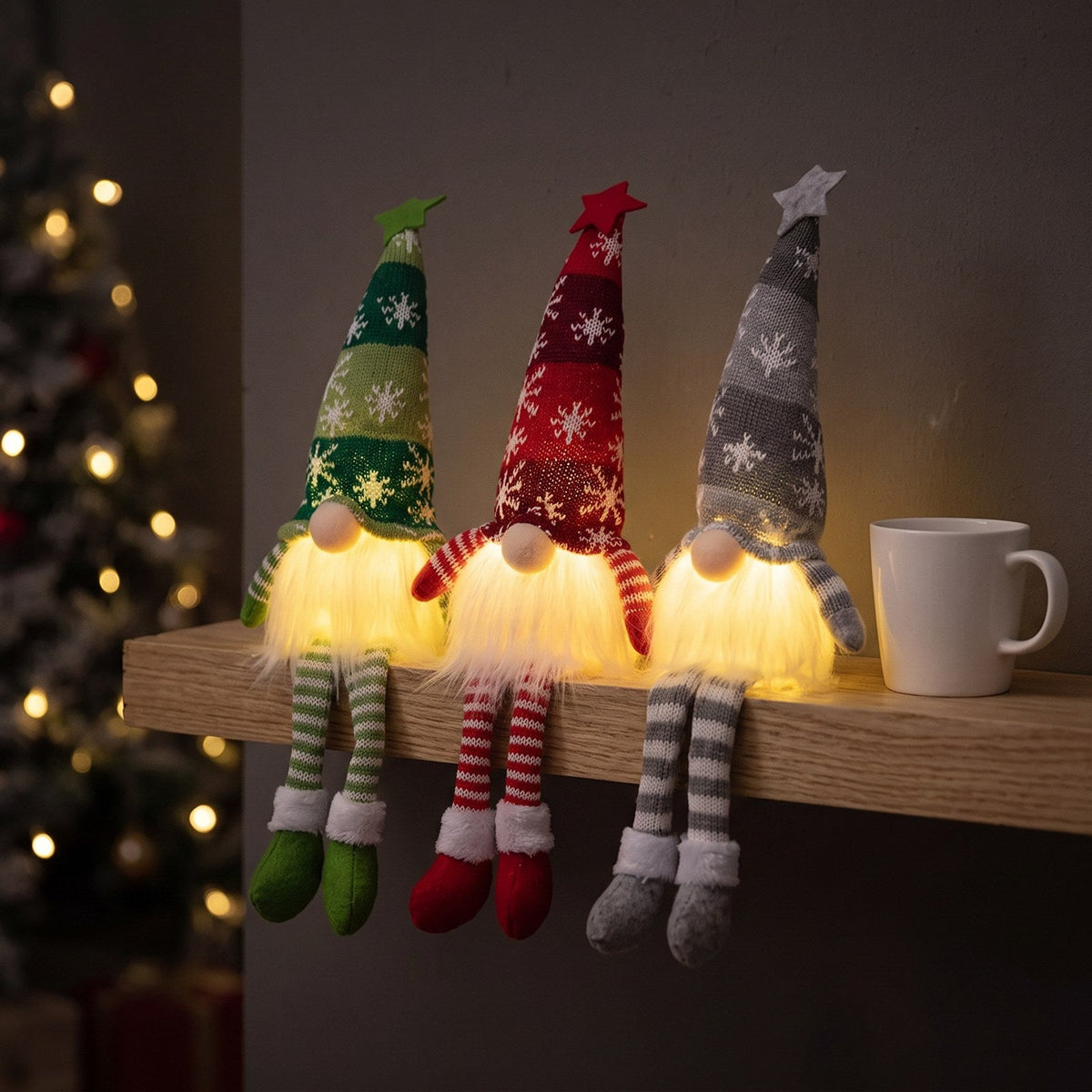 Three Long Legs gnomes glowing on a wooden shelf at night next to a mug
