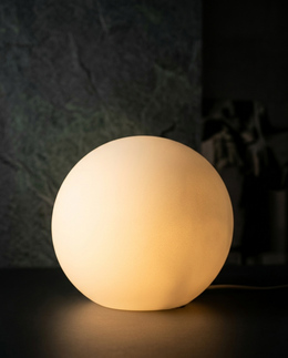 Sfera ball lamp glowing against a dark textured wall