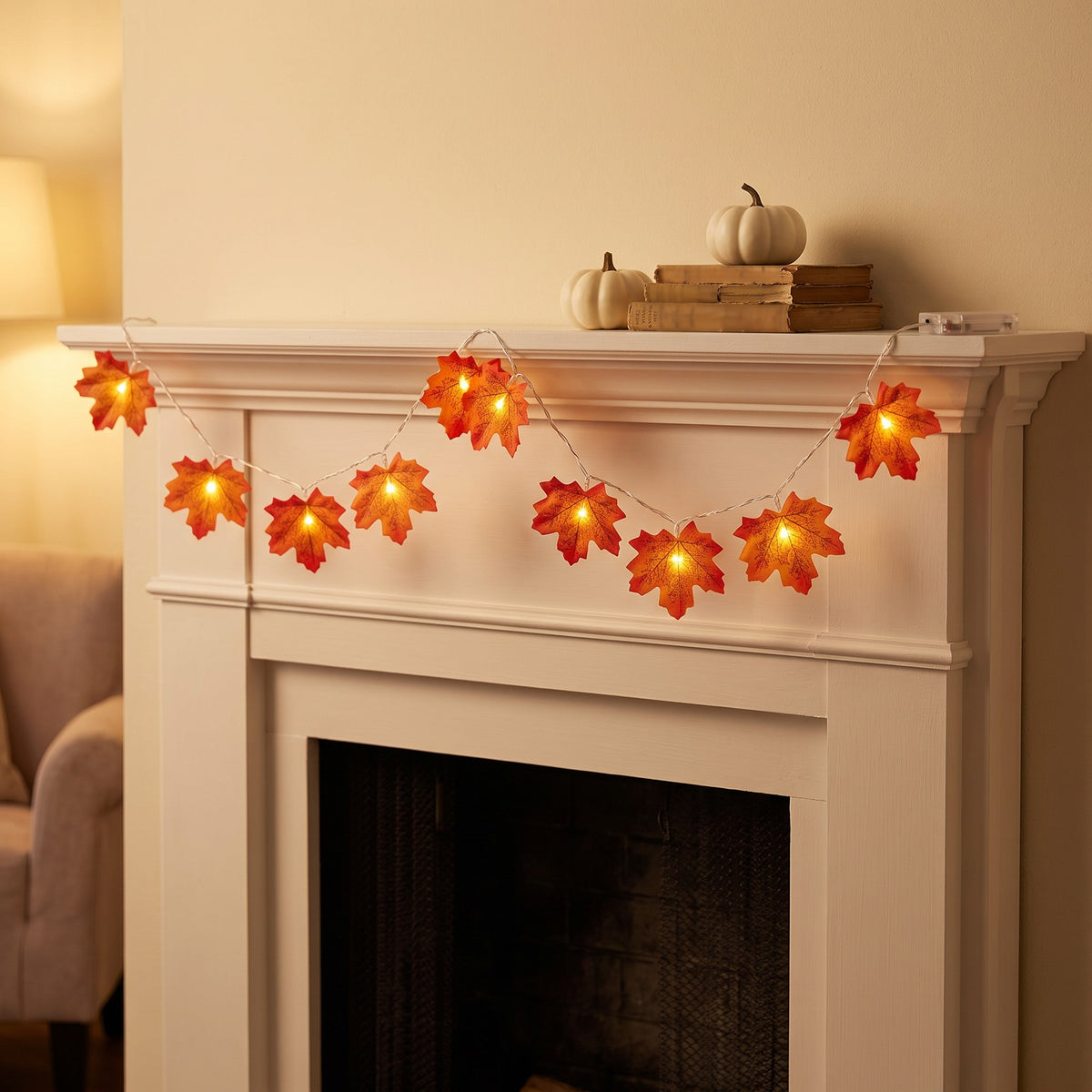 Styled scene: one LED maple leaf strand glowing along a white mantel with white pumpkins and old books (not included)