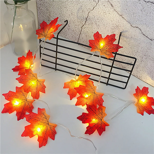 LED maple leaf strand switched on, draped over a wire rack on a white table