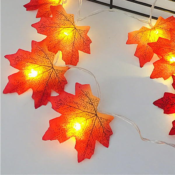 Four glowing maple leaves on a white table, close-up
